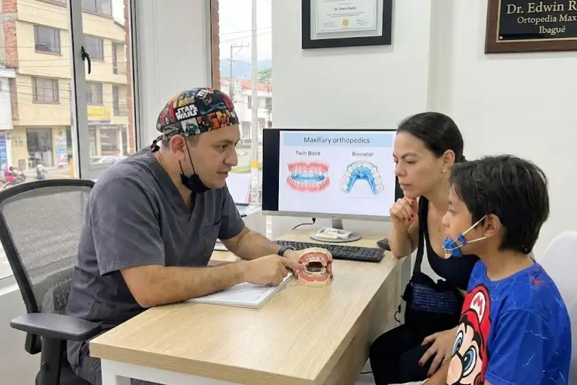 Dentista explicando tratamiento ortopedia maxilar niño y madre